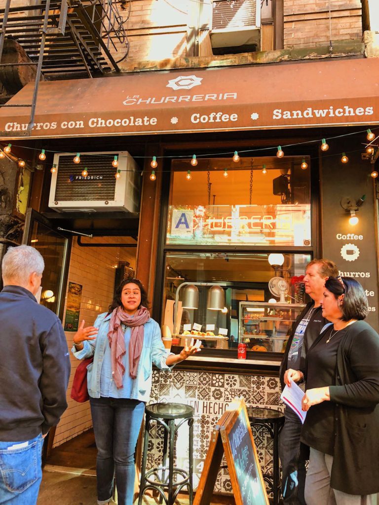 Image of a tour guide talking to a food tour in front of La Churreria in NoLita, NYC